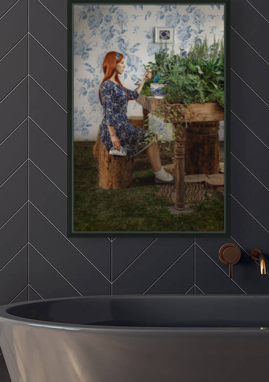 Young woman with red hair sitting on a wooden log in front of a porcelain soup tureen placed on a table covered with plants and flowers by Artmood Visualz