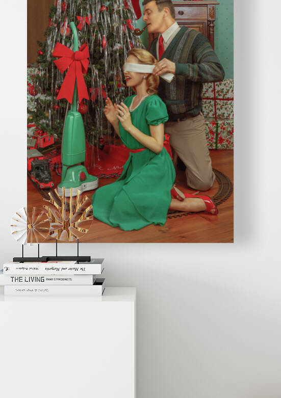 Vintage photography of a married couple from the 1950s in front of a Christmas tree and gifts the husband removing the blindfold from his wifes eyes to surprise her with a household appliance by Artmood Visualz