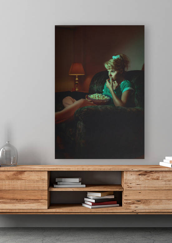 vintage lifestyle portrait of a young blonde woman in a late 80s early 90s interior decor eating popcorn andrelaxing on a sofa while watching television in the dark by Artmood Visualz