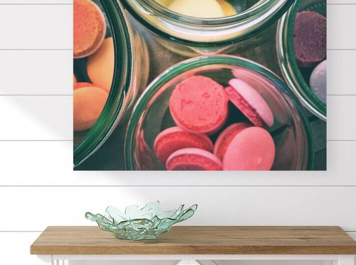 Close-up of multi colored macarons in glass jar on wooden table by Thevectoryfloor