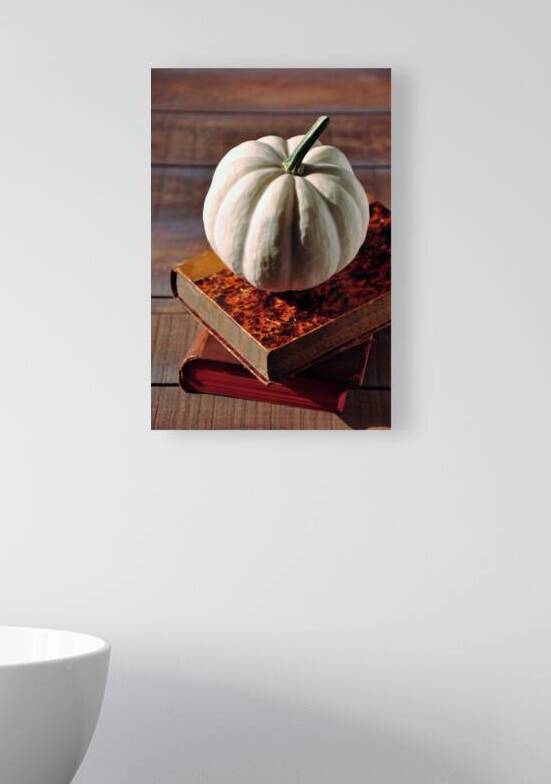 High angle view of white pumpkin on stack of old books on wooden table by Thevectoryfloor