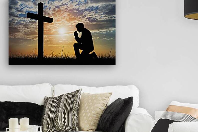 Silhouette of man praying to a cross with heavenly cloudscape sunset concept for religion worship love by Sergiu Gutium