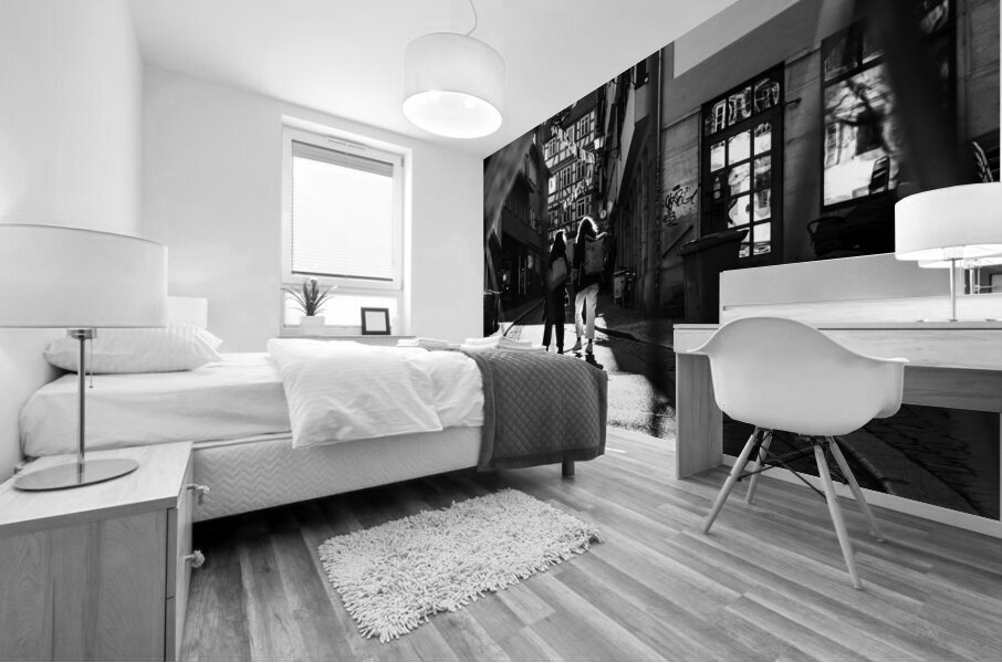 Black and white street photo of people walking down the road seen through the spokes of a bicycle Mural print