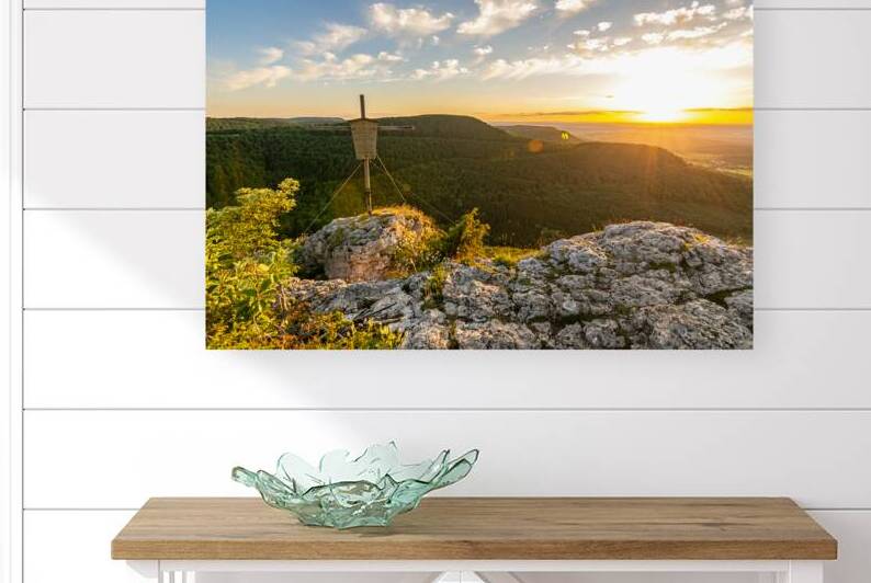 Beautiful sunset over a rock ledge and summit cross Wackerstein in the Swabian Alps in Southern Germany by caladoart