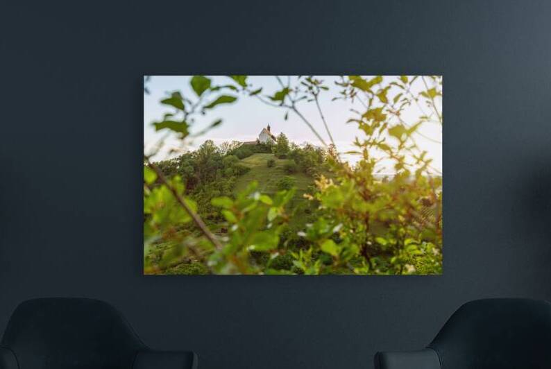 Picturesque chapel Wurmlinger Kapelle on a steep hill framed by scenic tree branches at sunset by caladoart