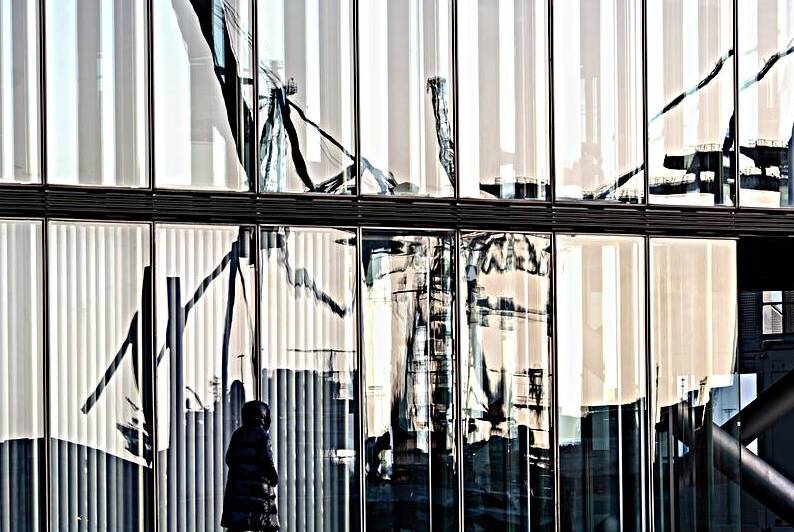 Harbor cranes reflecting in glass façade of modern building at the Elbe River in Hamburg  by caladoart