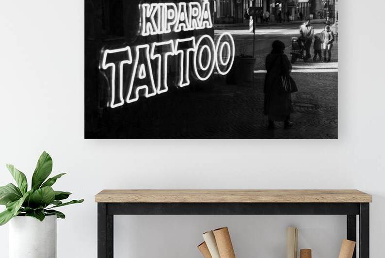 Black and white capture of the mirror image of an old woman and a family in the window of a tattoo studio   by caladoart