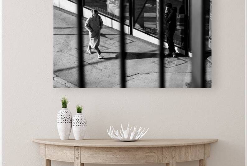 Black and white capture of a young woman walking down the street and looking at a man using his phone  by caladoart