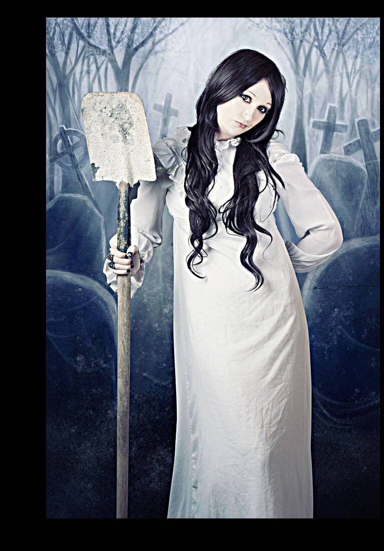 Spooky witch gravedigger with spade in graveyard Reproduction