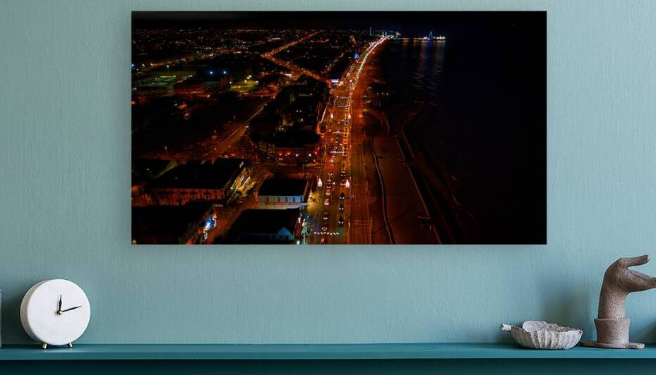 Aerial night view of a coastal city with illuminated streets and dark ocean waters in Backpool England. by Vasile Jechiu