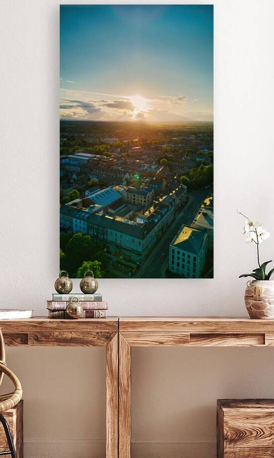 Aerial view of a cityscape at sunset with sun rays piercing through clouds highlighting urban architecture in Harrogate North Yorkshire. by Vasile Jechiu