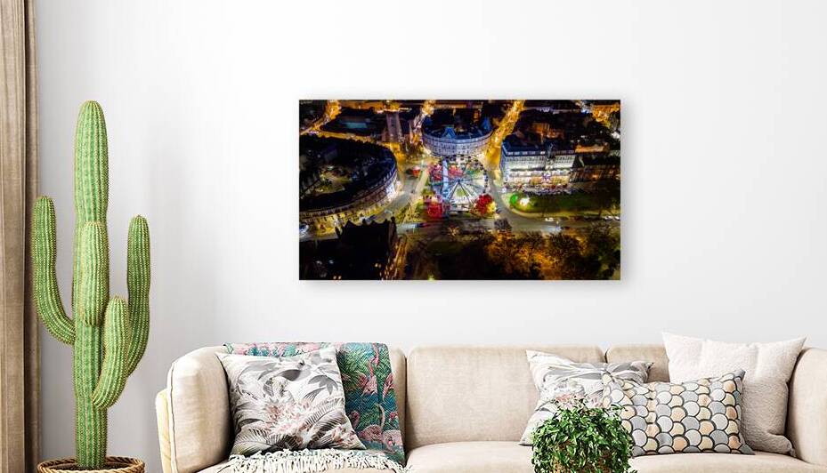 Aerial night view of a vibrant city fair with illuminated Ferris wheel and bustling streets surrounded by buildings in Harrogate North Yorkshire. by Vasile Jechiu