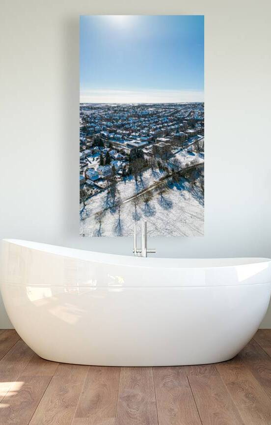 Winter aerial view of a suburban neighborhood with snow-covered houses and streets under a clear blue sky in Harrogate North Yorkshire. by Vasile Jechiu