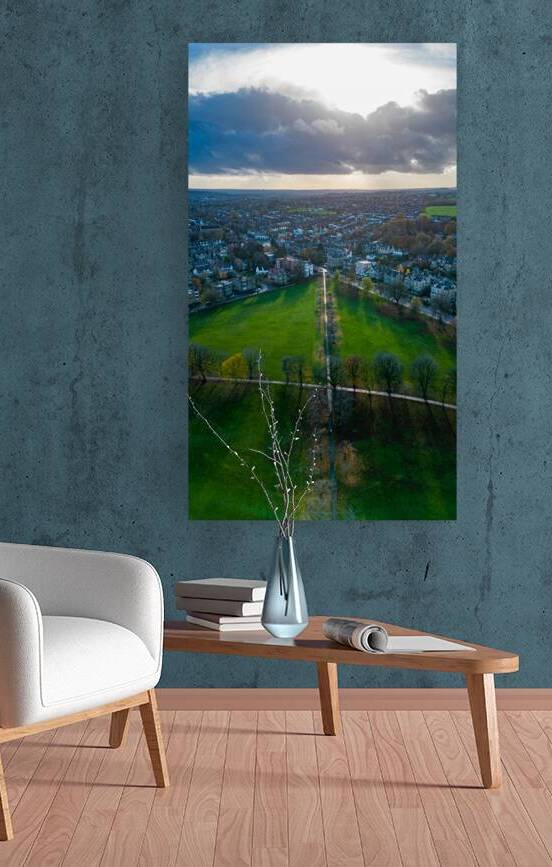 Aerial view of a cityscape with a road leading through green fields under a dramatic cloudy sky in Harrogate North Yorkshire. by Vasile Jechiu