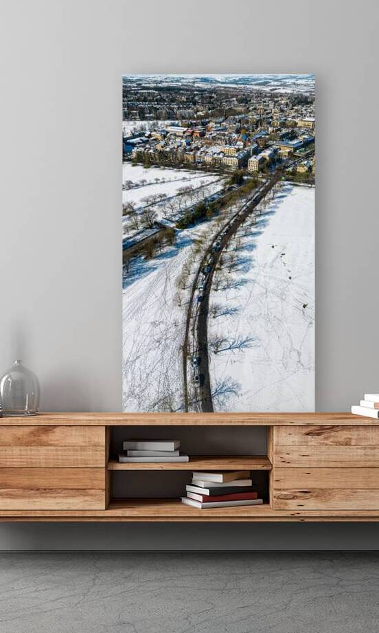 Aerial view of a train passing through a snowy landscape with a town in the background in Harrogate North Yorkshire. by Vasile Jechiu