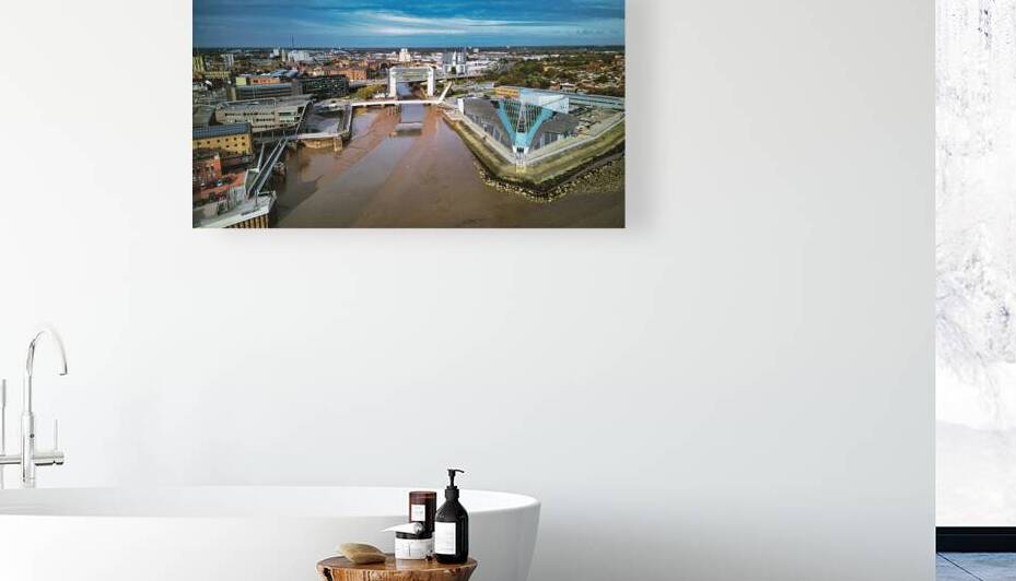 Aerial view of a modern flood barrier on a muddy river near an urban area under a cloudy sky in Hull England. by Vasile Jechiu