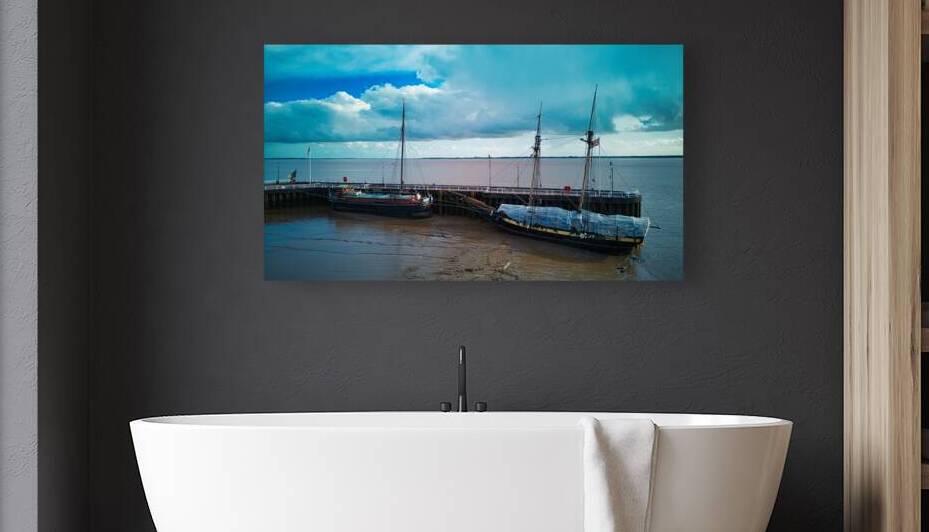 Vintage sailing ships docked at a wooden pier under a cloudy sky with calm waters and muddy shoreline in Hull England. by Vasile Jechiu