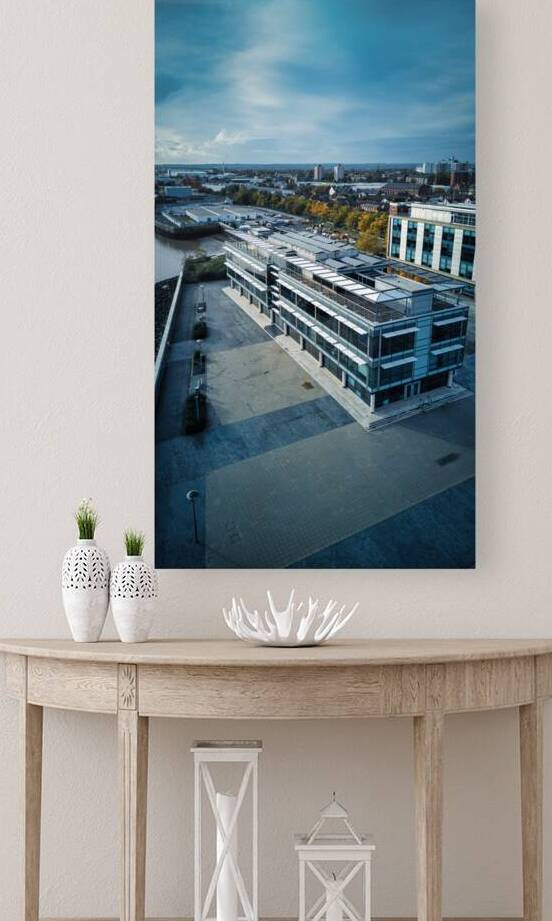 Modern office building with a rooftop terrace overlooking a river and cityscape under a cloudy sky in Hull England. by Vasile Jechiu