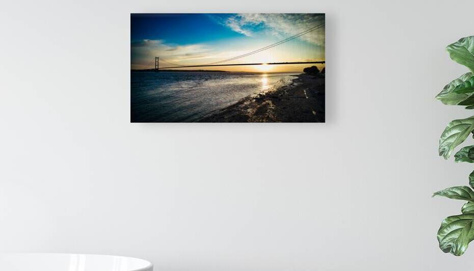 Suspension bridge silhouette at sunset with vibrant sky over calm river in Hull England. by Vasile Jechiu